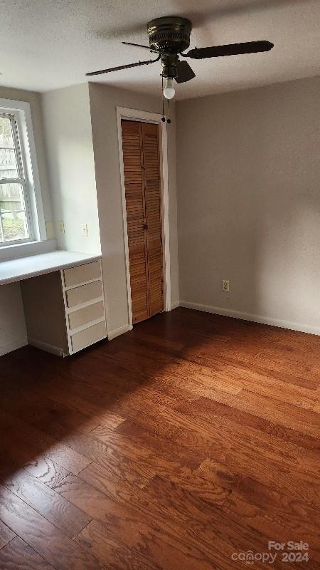 unfurnished bedroom featuring a textured ceiling, ceiling fan, and dark wood-type flooring