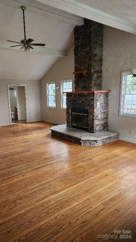 unfurnished living room featuring hardwood / wood-style floors, lofted ceiling with beams, plenty of natural light, and ceiling fan