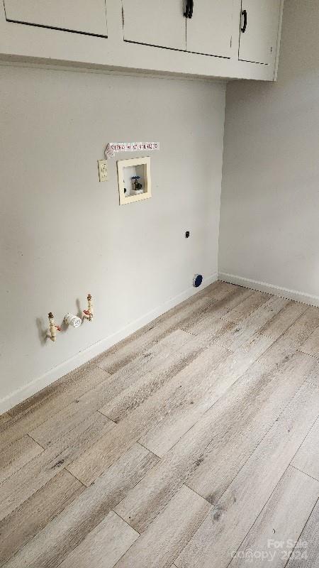 washroom with cabinets, washer hookup, light wood-type flooring, hookup for an electric dryer, and gas dryer hookup