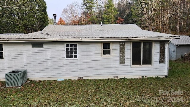 view of property exterior with central air condition unit and a yard