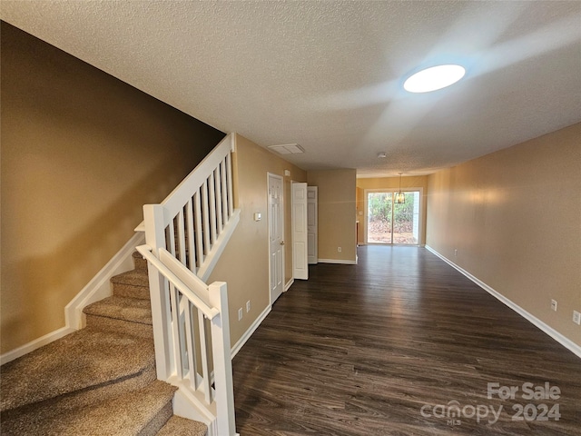 hall featuring a textured ceiling, a chandelier, and dark hardwood / wood-style floors