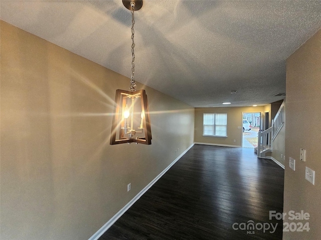 spare room featuring a textured ceiling and dark wood-type flooring