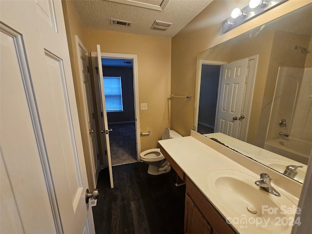 full bathroom featuring wood-type flooring, a textured ceiling, toilet, shower / washtub combination, and vanity