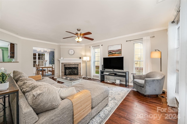 living room featuring a tiled fireplace, crown molding, ceiling fan, and dark wood-type flooring