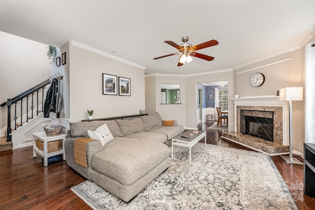 living room with ceiling fan, dark hardwood / wood-style flooring, ornamental molding, and a tiled fireplace