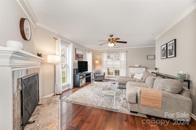 living room with hardwood / wood-style floors, ceiling fan, crown molding, and a tiled fireplace