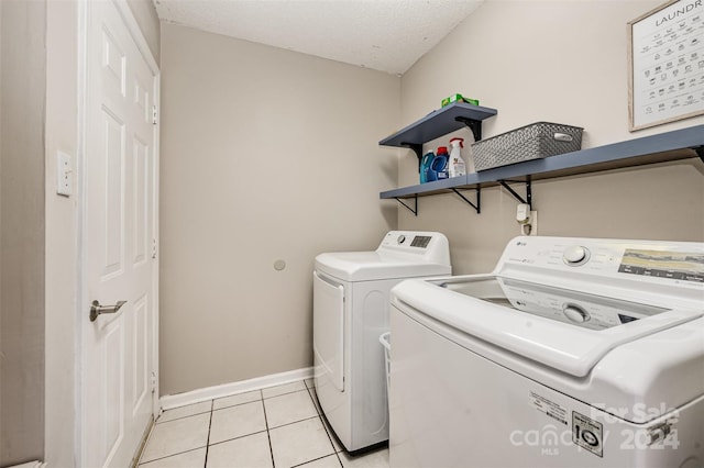 washroom featuring light tile patterned floors, a textured ceiling, and washing machine and clothes dryer