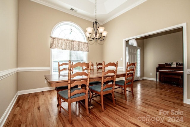 dining room with wood-type flooring, ornamental molding, and an inviting chandelier