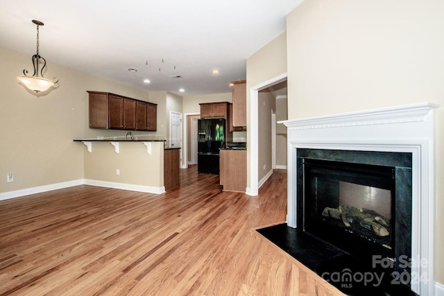 131 Quail Haven Dr, Troutman, NC 28166 - kitchen featuring black refrigerator with ice dispenser, a peninsula, a kitchen breakfast bar, dark countertops, and light wood finished floors