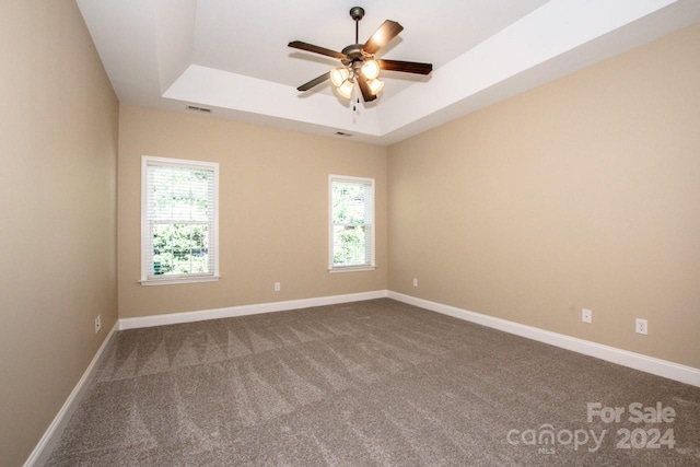 empty room with carpet, a raised ceiling, and ceiling fan