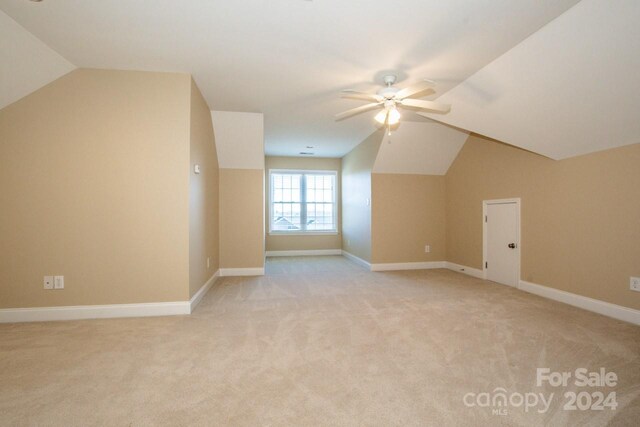 additional living space with light colored carpet, ceiling fan, and lofted ceiling