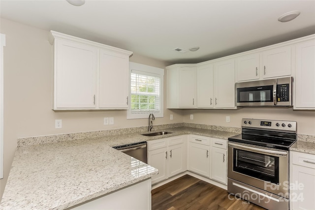 kitchen featuring dark hardwood / wood-style flooring, light stone counters, stainless steel appliances, sink, and white cabinets