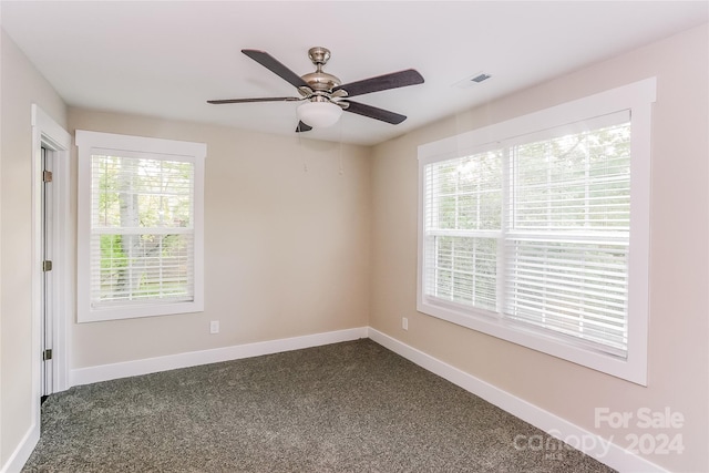 spare room with dark colored carpet and ceiling fan