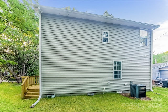 view of side of property featuring a yard and central AC