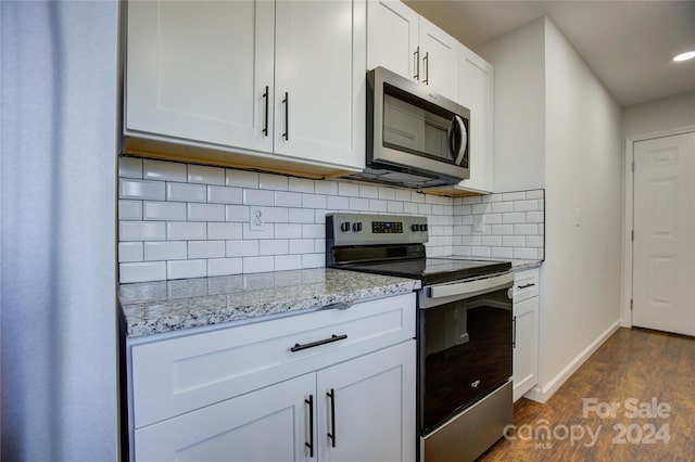 kitchen with light stone countertops, dark hardwood / wood-style floors, backsplash, white cabinets, and appliances with stainless steel finishes