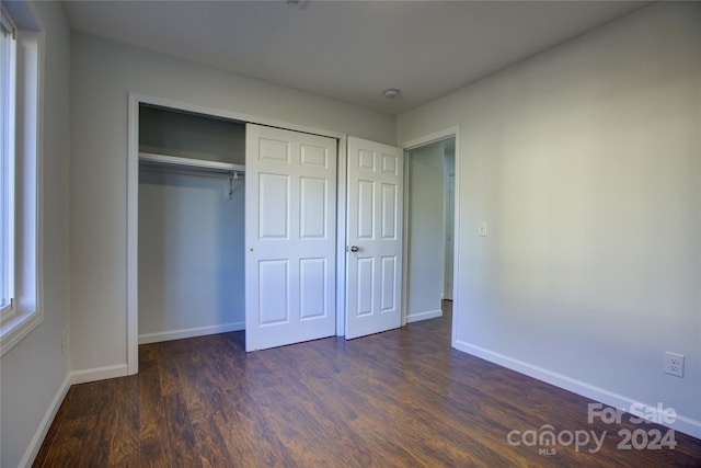 unfurnished bedroom featuring dark hardwood / wood-style flooring and a closet