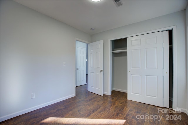 unfurnished bedroom with dark hardwood / wood-style flooring and a closet