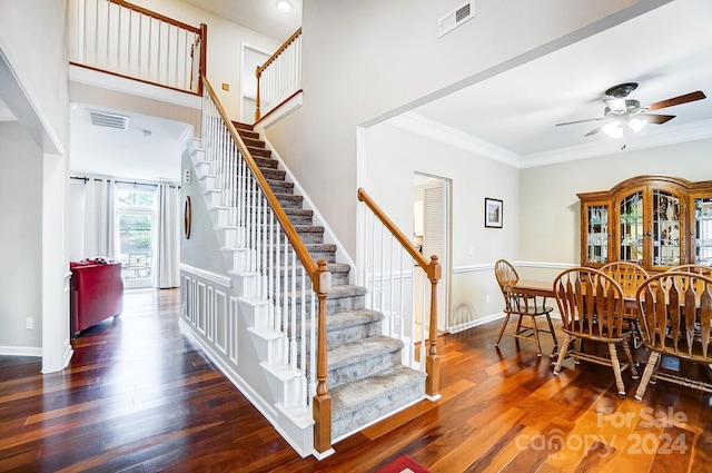 interior space featuring dark hardwood / wood-style floors, ceiling fan, ornamental molding, and a high ceiling