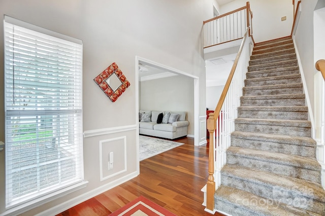 staircase with hardwood / wood-style floors and crown molding