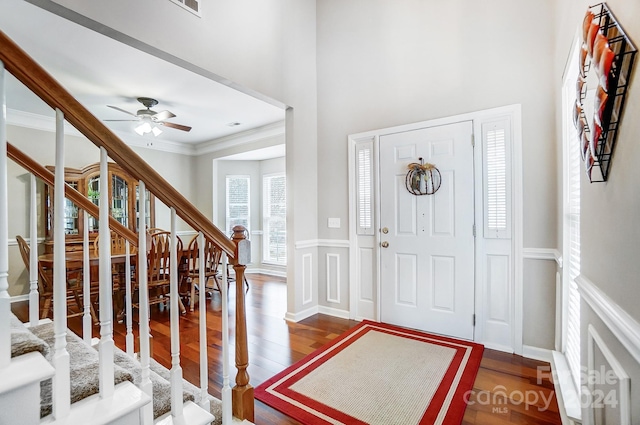 foyer featuring hardwood / wood-style floors, ceiling fan, a towering ceiling, and crown molding