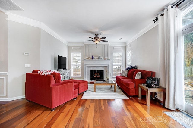 living room featuring wood-type flooring, crown molding, and a healthy amount of sunlight