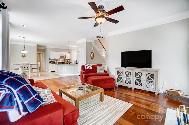 living room with hardwood / wood-style flooring, ceiling fan, and ornamental molding