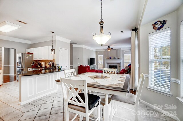 dining area with ceiling fan, light tile patterned floors, and crown molding