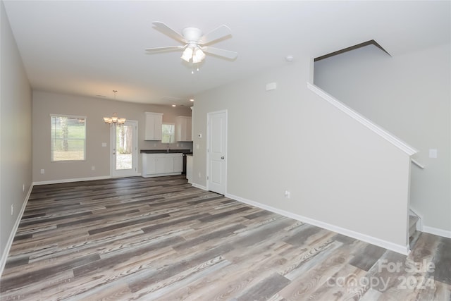 unfurnished living room featuring hardwood / wood-style floors and ceiling fan with notable chandelier