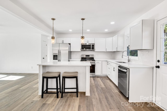 kitchen featuring a wealth of natural light, light hardwood / wood-style flooring, decorative light fixtures, and appliances with stainless steel finishes