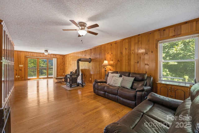 living room with ceiling fan, light wood-type flooring, and a wood stove