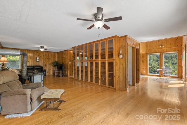 living room featuring ceiling fan, a textured ceiling, and light wood-type flooring