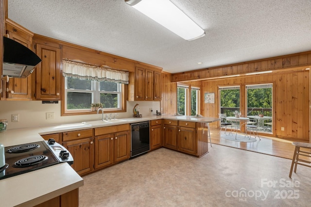 kitchen featuring dishwasher, sink, wooden walls, range hood, and kitchen peninsula