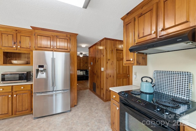 kitchen with a textured ceiling, stainless steel appliances, and wooden walls