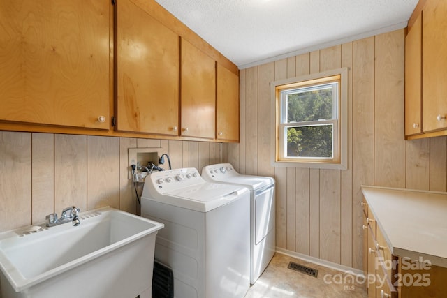 washroom featuring cabinets, washer and dryer, wooden walls, and sink