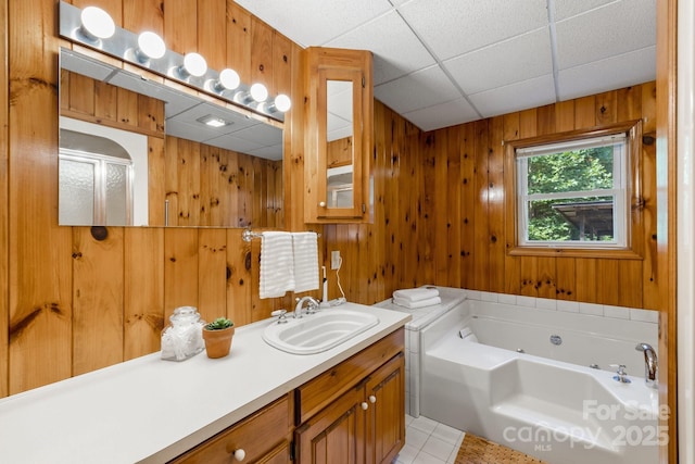 bathroom featuring plus walk in shower, tile patterned floors, a paneled ceiling, wooden walls, and vanity