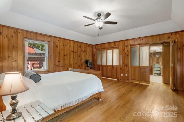 bedroom featuring ceiling fan, light hardwood / wood-style flooring, and a tray ceiling