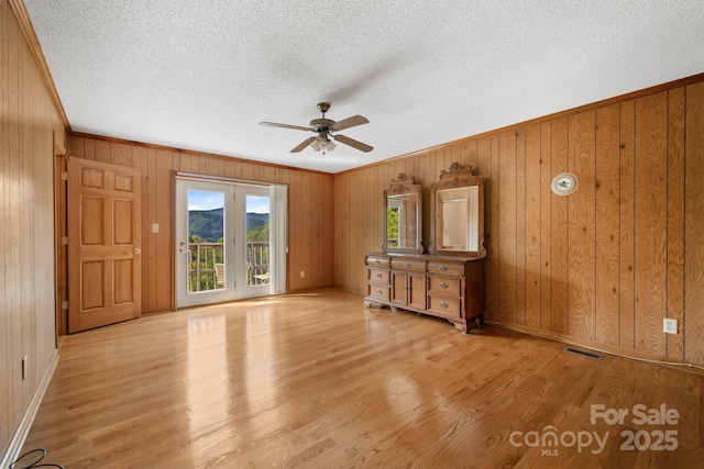 unfurnished living room featuring ceiling fan, wood walls, and light hardwood / wood-style flooring