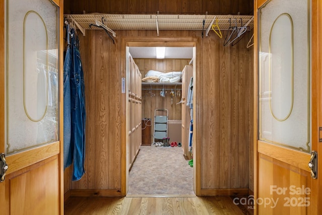 hallway featuring wooden walls and light hardwood / wood-style floors