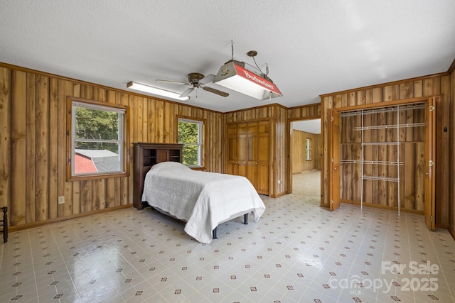 bedroom featuring ceiling fan, ornamental molding, and wood walls