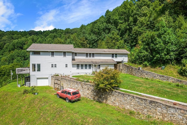 rear view of house with a garage, a yard, and a wooden deck