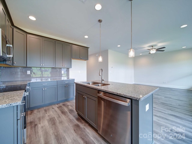 kitchen featuring appliances with stainless steel finishes, ceiling fan, sink, wood-type flooring, and decorative light fixtures