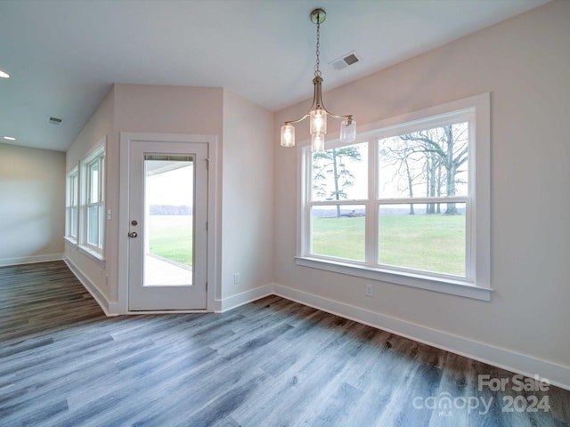 unfurnished dining area with a notable chandelier and wood-type flooring