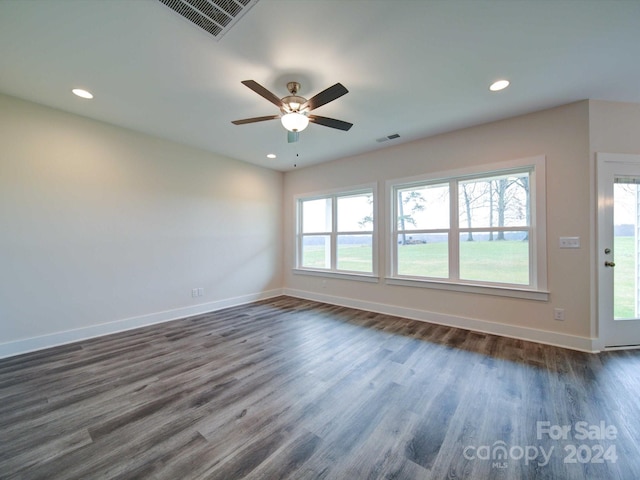 unfurnished room featuring ceiling fan, dark wood-type flooring, and a wealth of natural light