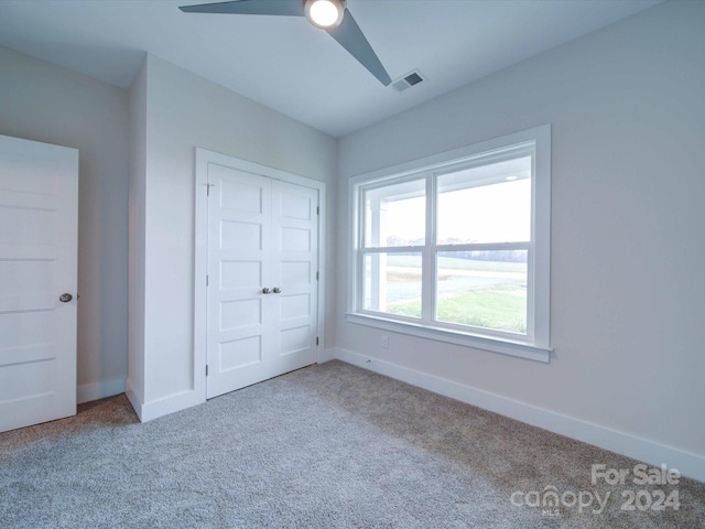 unfurnished bedroom with ceiling fan, a closet, and light carpet