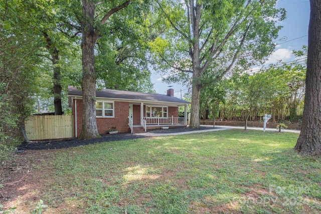 ranch-style home featuring covered porch and a front yard