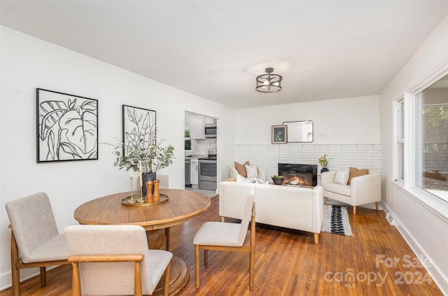 dining room featuring hardwood / wood-style flooring and a brick fireplace