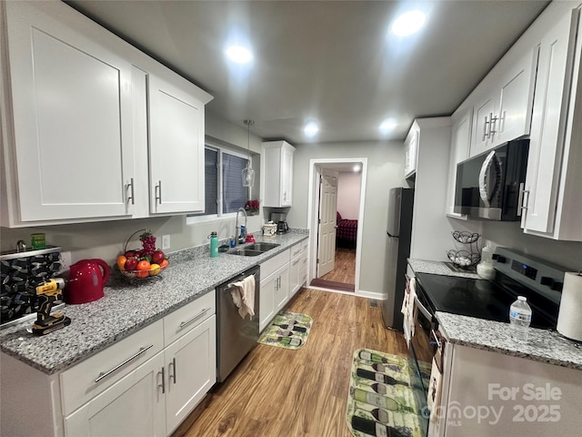 kitchen with light stone countertops, sink, stainless steel appliances, light hardwood / wood-style flooring, and white cabinets