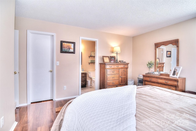 3076 Champion Ln SW, Concord, NC 28025 - bedroom with wood finished floors, connected bathroom, and a textured ceiling