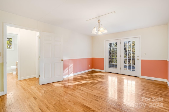 empty room featuring a notable chandelier and light hardwood / wood-style flooring