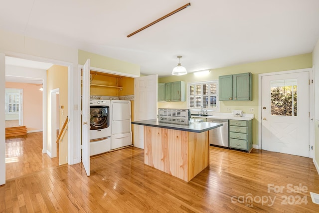 kitchen with a center island, green cabinets, stainless steel dishwasher, washer and clothes dryer, and light wood-type flooring